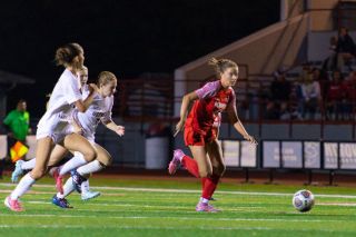Freshman winger Cameron Baker takes several defenders down the field as she speeds down the near sideline at Wortman Stadium during the Grizzlies 2-1 win over Glencoe on Monday, Oct. 6.##Nathan Ecker/News-Register