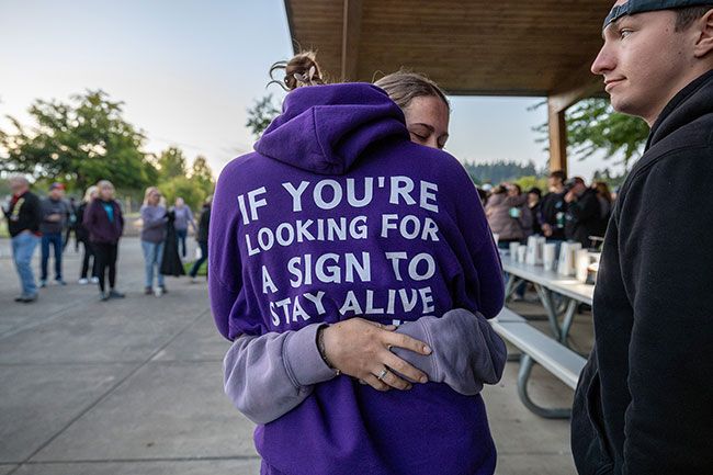 Rachel Thompson/News-Register##Shannon Shaver, left, and Jocelyn Middleton embrace during Thursday’s Out of Darkness Sunrise Vigil at Discovery Meadows Park in McMinnville. The McMinnville High School students — best friends of Mikalynn Morris — spoke before the Oregon Senate on May 19 in support of House Bill 3643, which established Oregon Youth Suicide Awareness Day in her memory. Shaver’s sweatshirt reads: “If you’re looking for a sign to stay alive, this is it. Call/text 988 for the 24/7 crisis hotline.” Rachel Thompson/News-Register##Shannon Shaver, left, and Jocelyn Middleton embrace during Thursday’s Out of Darkness Sunrise Vigil at Discovery Meadows Park in McMinnville. The McMinnville High School students — best friends of Mikalynn Morris — spoke before the Oregon Senate on May 19 in support of House Bill 3643, which established Oregon Youth Suicide Awareness Day in her memory. Shaver’s sweatshirt reads: “If you’re looking for a sign to stay alive, this is it. Call/text 988 for the 24/7 crisis hotline.”