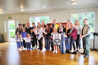 Emily Bonsant/News-Register##Yamhill County Sheriff’s Deputy Paul Baker’s children, grandchildren and great grandchildren pose for a photo Saturday in front of a highway memorial marker in his honor. At right is Sheriff Sam Elliott. Baker died at age 53 in a 1982 car crash while on duty near what was then the Bayou Golf Course.