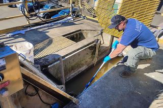 Emily Bonsant/News-Register##Lafayette Public Works Maintenance employee Zach Snyder uses a long-handled trash grabber to pull out “flushable” wipes that cling to the headwater screen at the wastewater treatment plant. The screen is no longer working, so twice daily public work employees have to collect the wipes — referred to as “rags.”