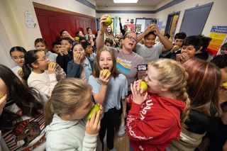 Rachel Thompson/News-Register##Duniway Middle School teacher Jena Mikkelborg, center, counts down to the time for everyone to simultaneously take a bite of a crispy Gem pear Tuesday morning. McMinnville students ate the fruit at once to celebrate eating fresh, locally farmed produce.