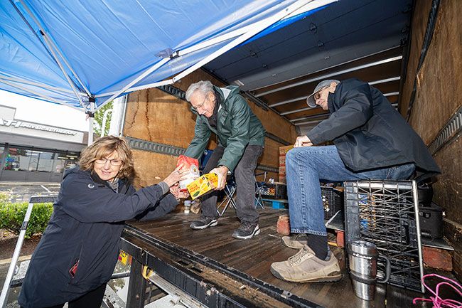 Rachel Thompson/News-Register##Rhonda Forest hands a bag of flour and a box of diced peaches to fellow volunteer Jim Herman as Gary Larson looks on during Saturday’s “Stuff the Truck” food drive at Grocery Outlet in McMinnville. The event marked a first-time partnership between the grocer and Hope on the Hill, a food pantry and clothing ministry based at McMinnville’s Nazarene Church on the Hill. The drive supported the group’s Thanksgiving outreach, including plans to distribute 230 turkeys and meal supplies to local families in need. “The reason we’re having to do this is because YCAP is being hit hard right now,” said board chair Joe Forest. “We’re one of YCAP’s biggest customers, and they’re really struggling. But the community is stepping up. I’ve had people just hand me hundreds of dollars and say, ‘Buy what you need.’ It’s such a blessing.” The effort yielded more than $500 in cash and 1,877 pounds of food. “Without Mike (McGinty of Grocery Outlet), it would not have happened,” Herman said. Donation details, including a link to the program’s Amazon registry, are available on the Hope on the Hill Facebook page.