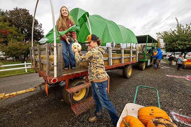 Rachel Thompson/News-Register##Kassidy Gui hands a white pumpkin to Asher Olliff of Dallas after a muddy trip through the patch at Heiser Farms on Saturday. The pair were making their way to the scales to weigh their picks. Heiser Farms, on Grand Island near Dayton, is open from 10 a.m. to 5 p.m. Saturdays and Sundays through Oct. 31. There is an admission charge. The u-pick pumpkin patch also is open on weekdays with free admission to buyers. Rachel Thompson/News-Register##Kassidy Gui hands a white pumpkin to Asher Olliff of Dallas after a muddy trip through the patch at Heiser Farms on Saturday. The pair were making their way to the scales to weigh their picks. Heiser Farms, on Grand Island near Dayton, is open from 10 a.m. to 5 p.m. Saturdays and Sundays through Oct. 31. There is an admission charge. The u-pick pumpkin patch also is open on weekdays with free admission to buyers.