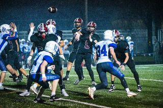 Rusty Rae/News-Register##Senior QB Ryan Mullins (No. 9) unleashes a pass through the rain during the Pirates 42-8 victory over Amity at Dayton High School on Friday, Oct. 31. The Halloween night contest offered several treats for the Pirates who secured a league title and undefeated regular season record.