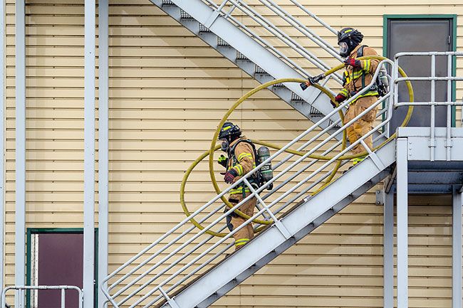 Rachel Thompson/News-Register##Firefighters haul hose down the stairwell of the drill tower. Firefighters and resident volunteers spent the day rotating through hands-on scenarios at two locations, practicing ventilation and fire attack at the drill tower and conducting search-and-rescue drills at a nearby house.
