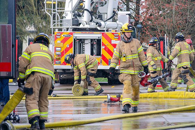 Rachel Thompson/News-Register##Firefighters coil hose and reset equipment between personnel rotations at the McMinnville Fire District’s drill grounds. The monthly joint training allows off-duty crews to practice ventilation, fire attack, and defensive operations in a controlled environment.