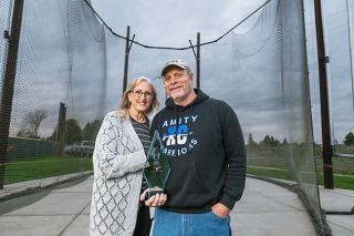 Rusty Rae/News-Register##Autumn Hayes (left) and Randy Hayes (right) pose for a photo while standing inside of Amity’s refurbished hammer ring. They are holding the USATF Coach of the Year award that was given to them for their outstanding work with track and field athletes in the community. Many local coaches and parents commended the couple for their selflessness as they provide a safe environment for students to become strong athletes and human beings.