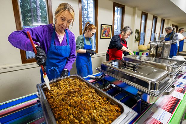 Rachel Thompson/News-Register##Lisa Sharp, who volunteers at the Soup Kitchen at St. Barnabas about twice a week, prepares to serve dressing at the Thanksgiving buffet.