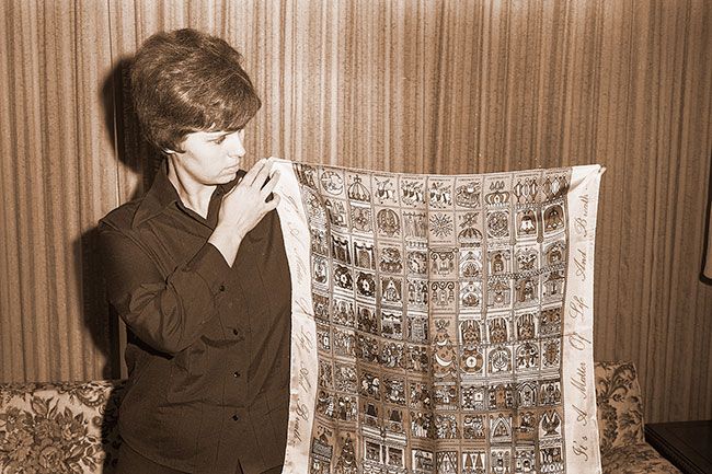 ##(Dec. 9, 1970) Mrs. Albert Winkler, McMinnville area chairman for the Willamette Tuberculosis and Respiratory Disease Association, shows Christmas Seal signature scarf, a gift from the Salem office. Scarf depicts a &ldquo;townscape&rdquo; in which designer Jerry Snyder, young California artist, has put together 100 different seals. In a complete sheet of the small seals for use during the holiday season one can find symbols such as the town clock, church doors, the wooden soldier, a parade and &ldquo;Hi&rdquo; over a front door.