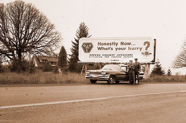 ##(Dec. 9, 1960) Officers from the McMinnville State Police detachment, Sgt. Al Cianni (left) and Patrolman Fred Kielhorn, check traffic flow with radar. In the background is a recently installed billboard inferring broadly that motorists should slow down. State Police have promised increased patrols over county highways and greater use of radar in an effort to prevent more accidents and deaths during the remainder of 1960.
