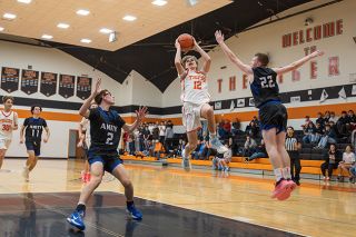 Rachel Thompson/News-Register##Tigers&rsquo; sophomore guard Chase Wald (No. 12) floats to the hoop as Amity junior guard Ethan Owings (No. 22) reaches out to block Wald&rsquo;s layup attempt during the intercounty matchup in the Tiger Dome on Tuesday, Dec. 16.
