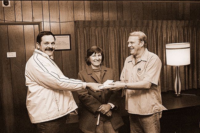 ##(Dec. 17, 1975) Mr. and Mrs. Robert Voepel of Amity accept checks from Norm Aldred of radio station KMCM. Checks are from citizens to help the Voepels and their five children after a fire destroyed their Amity-home and all its belongings Friday, Dec. 12. Appliances, clothing and furniture have also been donated. House was uninsured.