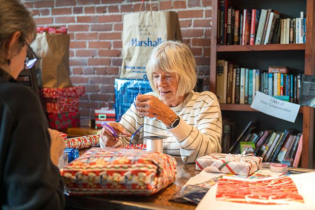 Rusty Rae/News-Register##Volunteer Janis Braich curls ribbons into a bow on a Christmas package she&rsquo;s wrapping for children in the Court Appointed Special Advocates (CASA) program. Community members donated the gifts and volunteers gathered during a work party at Two Dogs Taphouse on Monday, Dec. 15, to wrap and organize the presents for distribution.