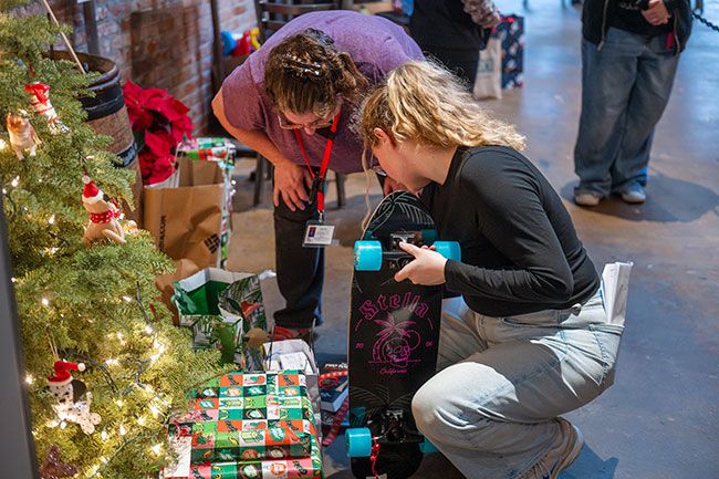 Rusty Rae/News-Register##lthea Beam and Ellie Vitukov of CASA sort through donated gifts next to Two Dogs&rsquo; Giving Tree. Patrons selected tags that hung on the tree. Each tag included the age and gender of a CASA client and what they hoped to get for Christmas.