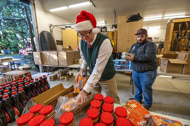 Rachel Thompson/News-Register##Carson Benner, owner of Cellar Ridge Construction, and Jaidon Wood help pack peanut butter, eggs, produce, ham and other items into boxes for delivery to local elementary and secondary schools so students will have food over the winter vacation. The construction company and partners Gormley Plumbing, Nice Electric, Portland Millwork, Builders First Source, Farnham Electric and Jesse Allen Construction contributed money to buy the food from Grocery Outlet. In addition to the 65 boxes they provided, another communitywide effort supplied more boxes to McMinnville High School so students and their families won&rsquo;t go hungry.