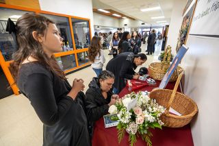Rachel Thompson/News-Register##From left, Nevaeh Grijalva, her mother Amanda, and Flicka Lucero write messages to the Hughes family during a memorial for Willamina Middle School vice principal Mike Hughes on Friday at Willamina High School. Neighbors of the Hughes family, Nevaeh &mdash; who had recently become one of Hughes&rsquo; students at the middle school &mdash; recalled talking with him recently about riding horses. Amanda said she wrote her message to reassure Hughes&rsquo; wife, Heather, &ldquo;to make sure she knows we&rsquo;re always there.&rdquo;