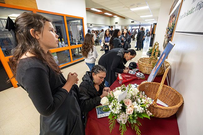 Rachel Thompson/News-Register##From left, Nevaeh Grijalva, her mother Amanda, and Flicka Lucero write messages to the Hughes family during a memorial for Willamina Middle School vice principal Mike Hughes on Friday at Willamina High School. Neighbors of the Hughes family, Nevaeh &mdash; who had recently become one of Hughes&rsquo; students at the middle school &mdash; recalled talking with him recently about riding horses. Amanda said she wrote her message to reassure Hughes&rsquo; wife, Heather, &ldquo;to make sure she knows we&rsquo;re always there.&rdquo;