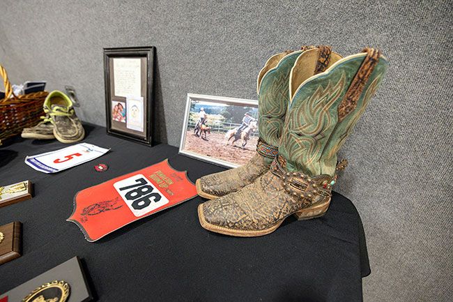 Rachel Thompson/News-Register##A pair of well-worn cowboy boots belonging to Mike Hughes sits on display alongside photos and personal items during his memorial service Friday, Dec. 19, at Willamina High School. Hughes, a longtime educator, coach and rancher, was remembered for his deep love of family, students and the Willamina community.