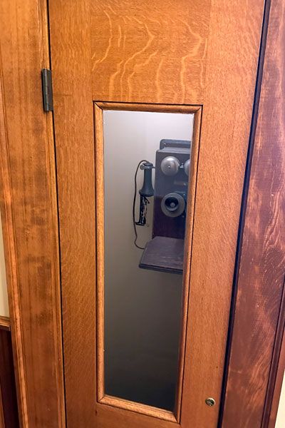 Kirby Neumann-Rea/News-Register##Antique lobby phone booth now locked in Butler Building, &ldquo;1&rdquo; etched on the door, was a tight squeeze in its day.