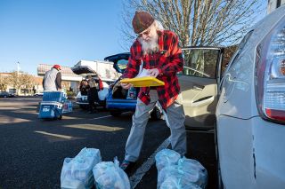 Rachel Thompson/News-Register##Meals on Wheels volunteer Daryll Alt checks his list of clients before heading out on his delivery route on Dec. 31. He was delivering not only that day&rsquo;s hot meal, but frozen ones for the homebound seniors to eat over the long holiday weekend.