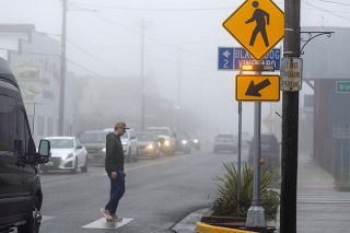 Rachel Thompson/News-Register##A recently installed crosswalk signal in Lafayette flashes as pedestrian Johnathon Waters of Lafayette crosses the intersection of Third and Bridge Streets on the foggy morning of Wednesday, Jan. 14. The new signal is part of the Bridge Street renovation project, which includes road repairs, sidewalk expansion, and ADA ramps.