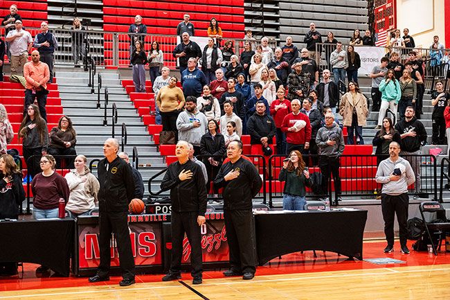 Rusty Rae/News-Register##Surrounded by basketball fans, referees and others, Adeen Willis sings the national anthem before a girls&rsquo; basketball game in the McMinnville High School gym. Mac High singers perform the anthem live before sporting events; most schools use recorded music.