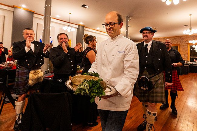 Rachel Thompson/News-Register##Chef Brett Uniss, culinary director at The Ground, carries a tray of haggis into McMinnville&rsquo;s The Grand on Saturday during the annual Burns Supper hosted by the Celtic Heritage Alliance. Behind him is presenter Preston Marshall, who later delivered the traditional &ldquo;Address to a Haggis,&rdquo; followed by Brandon Rose carrying a tray of whisky. The ceremonial procession is a central custom of the celebration honoring Scottish poet Robert Burns. Traditionally made from minced sheep organs mixed with oats, onions and spices and cooked in a natural casing, haggis is served ahead of an evening of music, food and toasts.