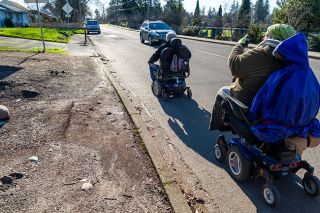 Branden Andersen/Newsberg##Newberg Mayor Bill Rosacker and local resident Jessy Phares-Cunningham wait for a safe place to cross the street to reach a paved sidewalk, and play &ldquo;Frogger&rdquo; until then during a December journey across town.