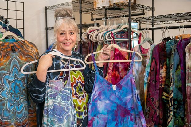 Rusty Rae/News-Register##Kelley Sharp of Yamhill holds up some of her tie-dyed clothing, which she sells through her We the Colorful Facebook page. Right: Sharp sprinkles dye over ice topping a garment that&rsquo;s been tied so some areas are protected from the color. As the ice melts, the dye soaks into the fabric.