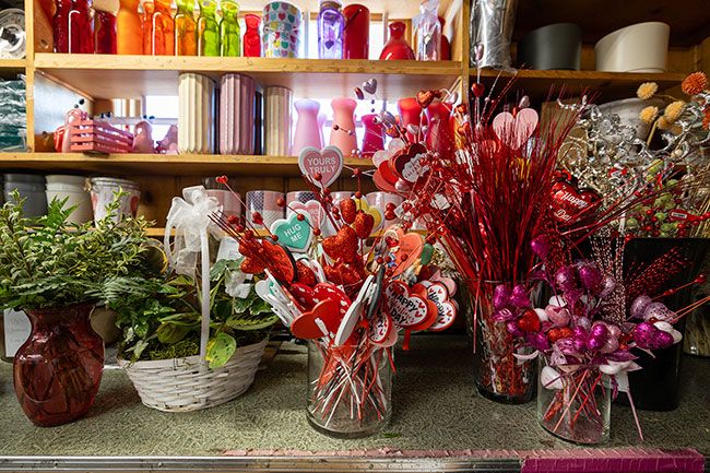 Rachel Thompson/News-Register##Audry Bernards and Hargis trim stems and strip greenery from flowers to get them ready for arrangements that can be decorated with heart-shaped messages and other embellishments.