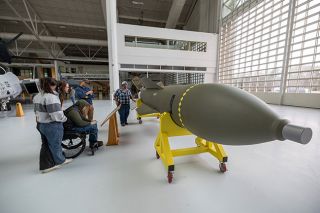 Rachel Thompson/News-Register##Evergreen museum visitors study the GBU-57 MOP bomb, the newest exhibit in the Titan Pavilion, formerly called the space museum. The bomb, the U.S.&rsquo;s largest non-nuclear weapon, is an inert training model so crews could practice attaching it to a B-2 bomber. Loaded with more than 5,000 pounds of explosives, GBU-57s were used in an attack on Iran&rsquo;s nuclear development labs in June 2025.