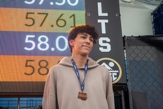 Nathan Ecker/News-Register##Ko Depweg graces the podium inside Tualatin Hill Aquatic Center with the bronze medal from his 100-yard breaststroke record performance around his neck.