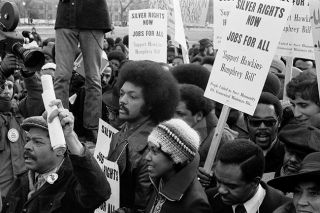 Thomas J. O&rsquo;Halloran/Wikicommons##
Jesse Jackson surrounded by marchers carrying signs advocating support for the Humphrey-Hawkins Act for full employment, near the White House, Washington, D.C., on Jan. 15, 1975.
