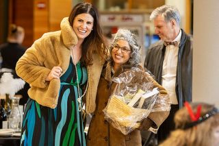 Rachel Thompson/News-Register##Lacey Summers hugs Katie O&rsquo;Brasky, who holds a raffle basket she won, during the McMinnville Lions Club&rsquo;s third-annual Roaring Night of Giving on Feb. 21 in the Evergreen Theater lobby. The 1920s-themed fundraiser raised $18,000 for McMinnville High School&rsquo;s student resource room and Lions projects.