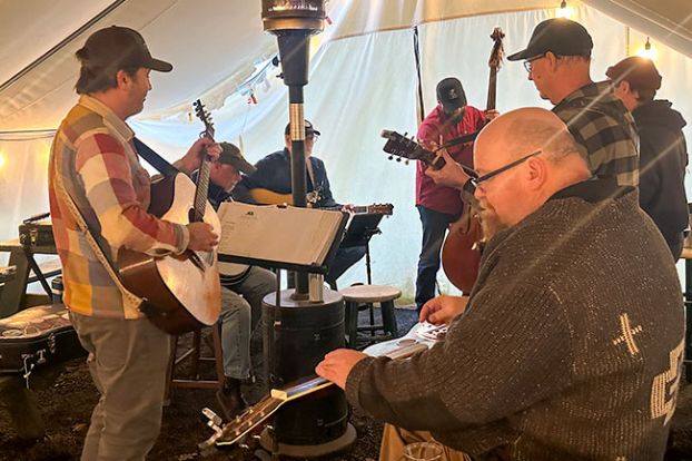 Kirby Neumann-Rea/News-Register##Bluegrass jams are suspended at the Wolves & People farmhouse, but owner Christian DeBenedetti, left, hosted regulars under a tent for the final session of the season.