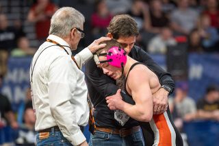 Rusty Rae/News-Register##Bulldogs&rsquo; senior Kisor Savage is embraced by coaches Barry Wilson and Ariah Fasana after his title victory at 138 pounds.