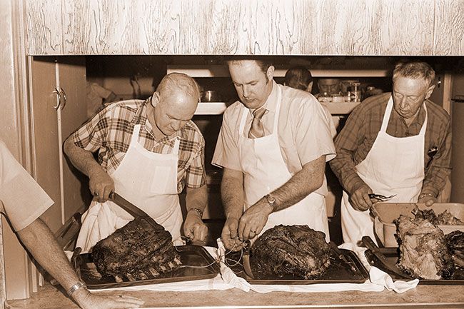 ##(March 3, 1971) McMinnville firemen and their wives were feted by the Chamber of Commerce last week at an annual dinner held at the Fire Hall. Here, chamber members (I-r) Bud Traster, Curt Bresee and B. A. McPhillips help prepare food. Banquet is held in appreciation for firemen&rsquo;s work in setting up Christmas decorations each year.