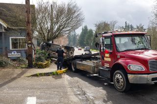 Rachel Thompson/News-Register##McMinnville Police Officer Robert Harmon oversees the towing of a Toyota Highlander outside the St. Vincent de Paul Social Services office at the corner of Southwest Adams Street and Southeast Handley Street. On Thursday afternoon, a two-vehicle collision took place at the intersection and collided with the building.