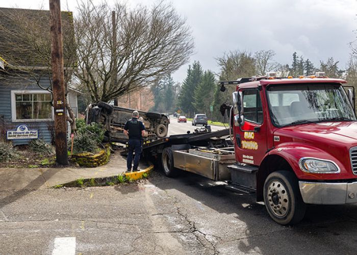 Rachel Thompson/News-Register##McMinnville Police Officer Robert Harmon oversees the towing of a Toyota Highlander outside the St. Vincent de Paul Social Services office at the corner of Southwest Adams Street and Southeast Handley Street. On Thursday afternoon, a two-vehicle collision took place at the intersection and collided with the building.