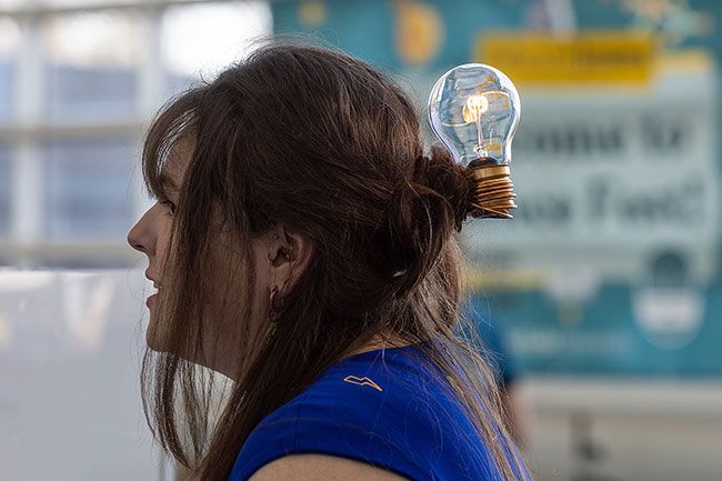 Rachel Thompson/News-Register##Amy Simpson of Simpson Property Services sports a rechargeable LED lightbulb in her hair while working a booth at ScienceFest 26, held Saturday at Evergreen Aviation & Space Museum.