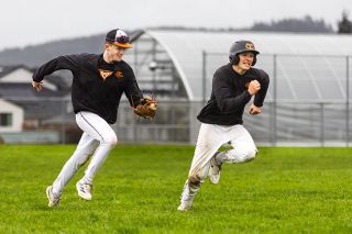 Nathan Ecker/News-Register##Yamhill Carlton junior and prospective starting shortstop Porter Carden chases down fellow junior Liam McGuire during a rundown drill on a soggy March afternoon at Yamhill Carlton High School. In practices, the Tigers are having fun, which players and coaches are interested to see translate into regular season games.