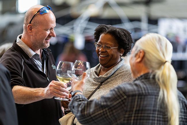 Rachel Thompson/News-Register##Jeremy and Shawn Taylor of Tigard raise their glasses with Duc Tran of Dayton. The annual Wine & Food Classic, a fundraiser for St. James School, features Oregon wineries, chefs, brewers, distillers and artisans. For the first time, the annual event expanded into both the Hercules and Titan pavilions.