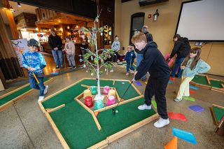 Rachel Thompson/News-Register##With school out this week, Conner Drorbaugh, 11, of McMinnville lines up a putt as his cousins Weston Owens, 9, of Amity, left, and Callynn, 7, right, take their turns at the Sweet Spot pop-up mini golf course inside the KAOS Building at Third and Galloway.