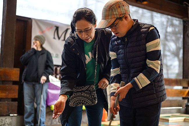 Rachel Thompson/News-Register##Olivia Shingledecker of McMinnville lends a hand as her son, Abraham, takes a turn on the course. Abraham also golfs with his father, Howard, at The Nines.