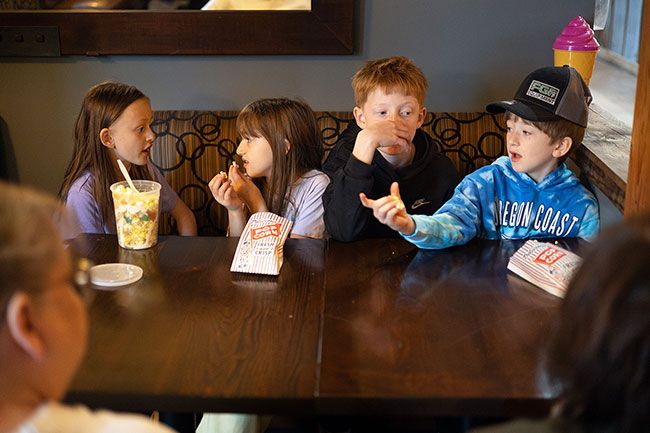 Rachel Thompson/News-Register##After a round of mini golf, cousins Stella Drorbaugh, 8, Callynn Owens, 7, Conner Drorbaugh, 11, and Weston Owens, 9, share popcorn and stories at the Sweet Spot pop-up course in McMinnville as their grandmothers, Ronda Taft and Peggy Owens, listen in from across the table.
