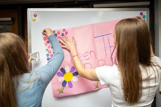 Rachel Thompson/News-Register##Patton Middle School volunteers Willa Fagan, left, and Hannah Malstrom post a sign inviting sixth- through eighth-graders to a pop-up clothing shop at the McMinnville Public Library Tuesday.