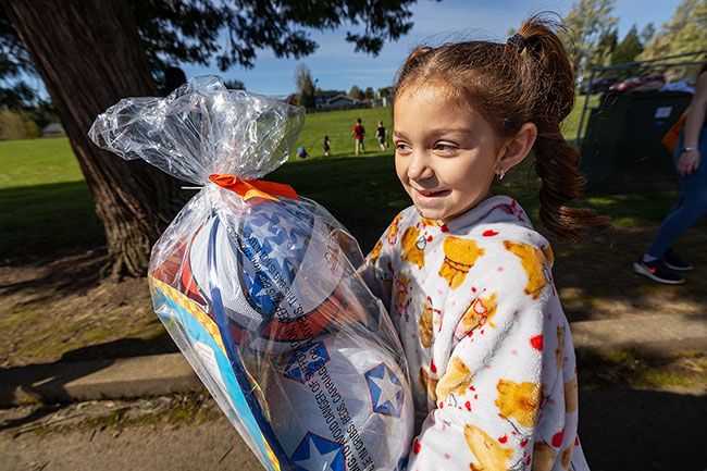 Rachel Thompson/News-Register##Eight-year-old Marcelia Vargas of Dayton grins as she carries a prize basket after finding a winning egg during the hunt at Dayton Grade School.