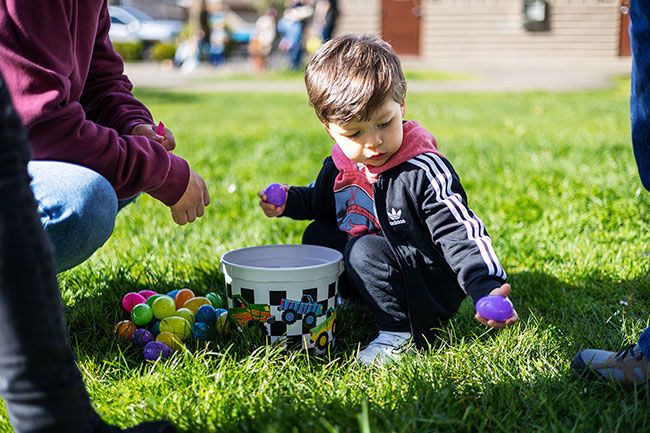 Rachel Thompson/News-Register##Adriel Atrian, 3, of Dayton sorts through plastic Easter eggs collected in his monster truck bucket after the egg hunt in the park.