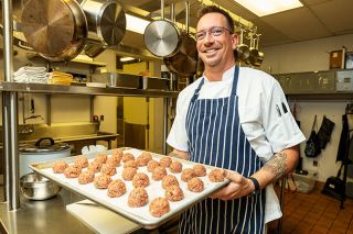 Rachel Thompson/News-Register##Chef Waylon Zabriskie prepares to slide a tray of beef and pork meatballs into the oven for his new business, Prep Chef, which sells premade meals that can be reheated at home in the oven or microwave.