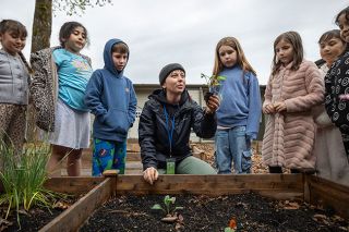 Rachel Thompson/News-Register##Visiting educator Aubryn Walters, center, shows second-graders how to separate three seedlings growing in the same pot so that each can be planted separately. Walters lives in Washington, D.C., but was visiting Newby, her former elementary school.